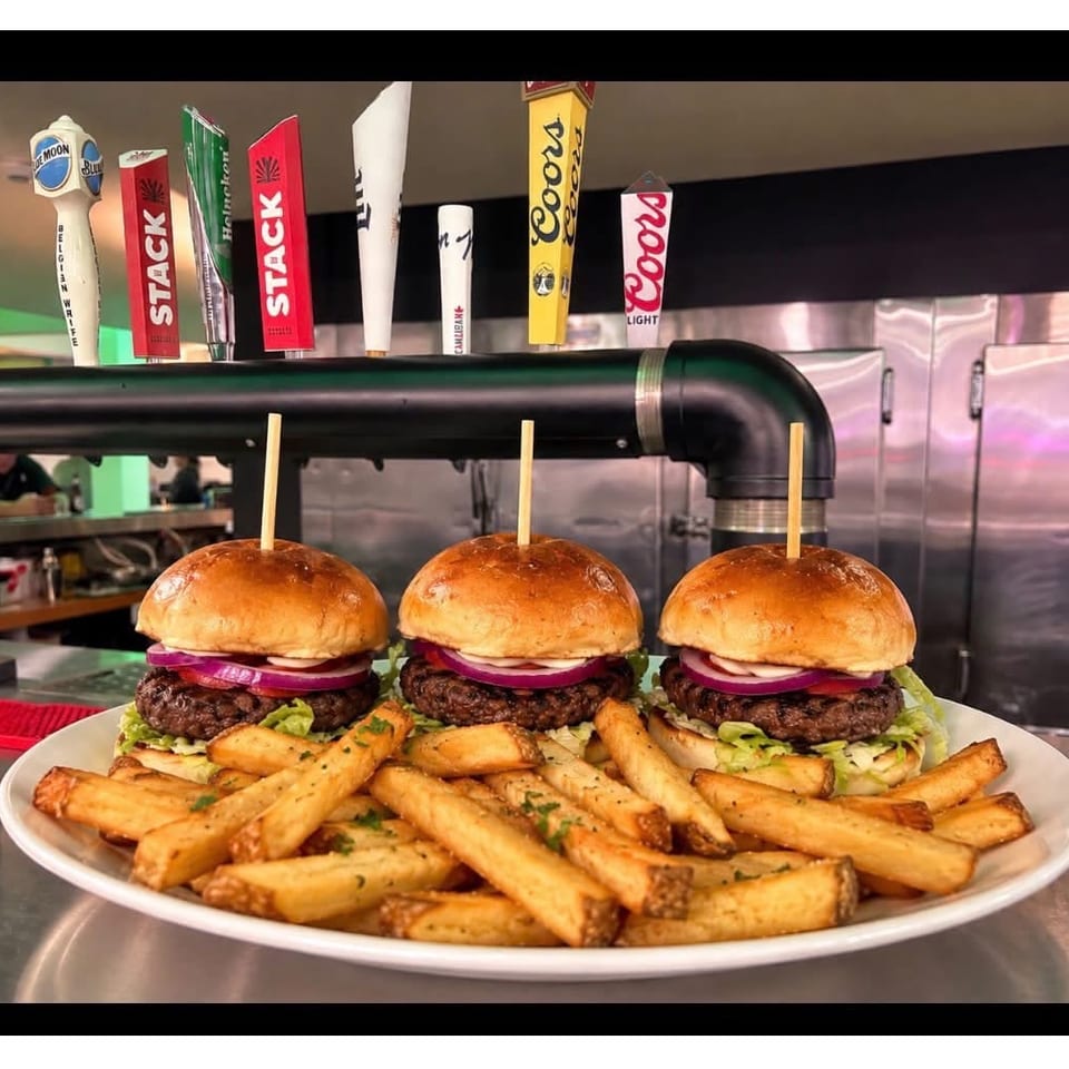 Three burgers with fries at the bar
